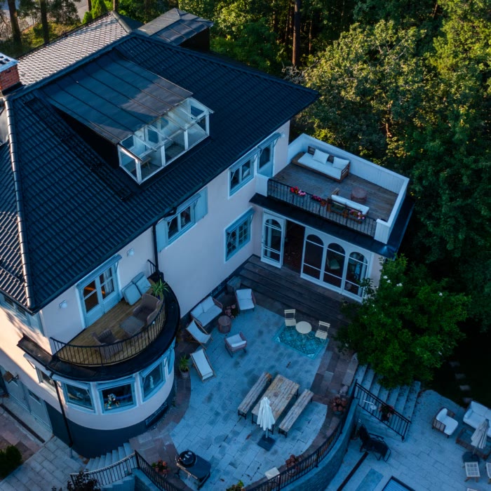 Vit villa med svart tak och takterrass, drönarbild