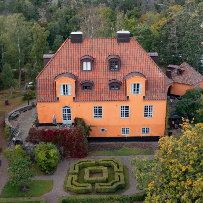 Drönarbild av gul herrgård med rött tegeltak och takkupor