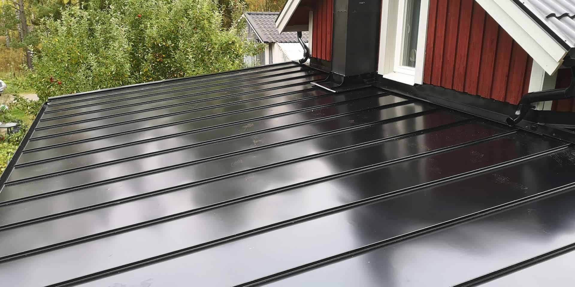 Svart falsat plåttak vid en röd trävilla