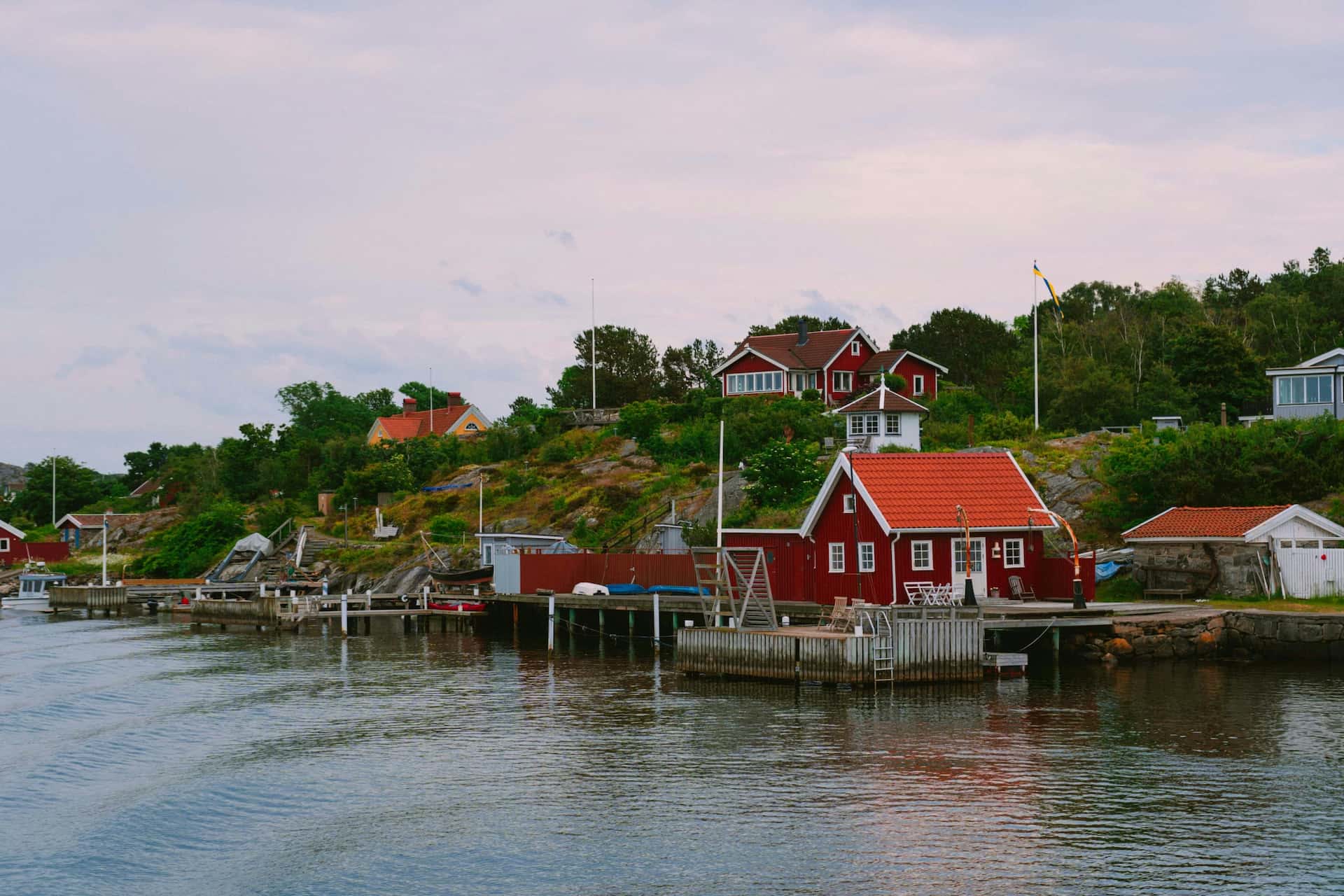 Röda sjöbodar och hus med tegeltak vid vattnet